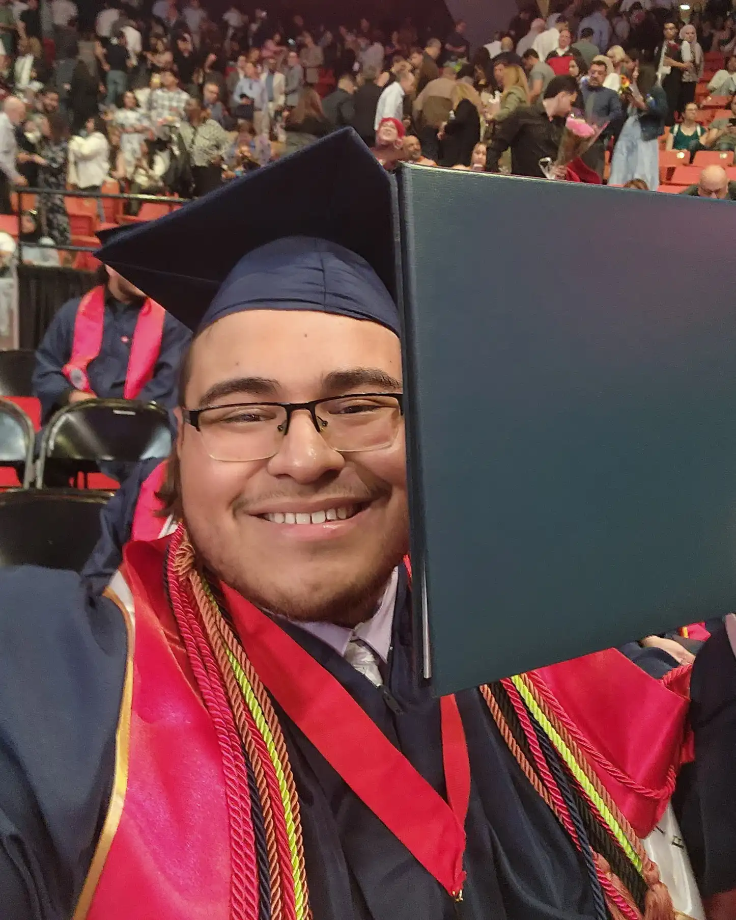 Green Halo Scholar Alex C posing in cap and gown with his diploma