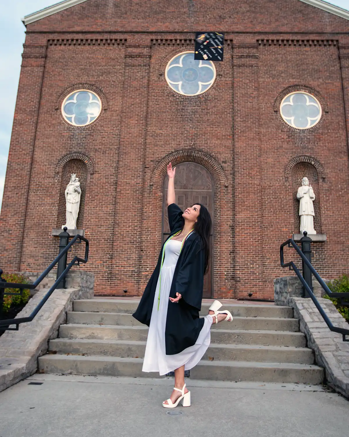 Green Halo Scholar Nubia in cap and gown tossing her cap in celebration